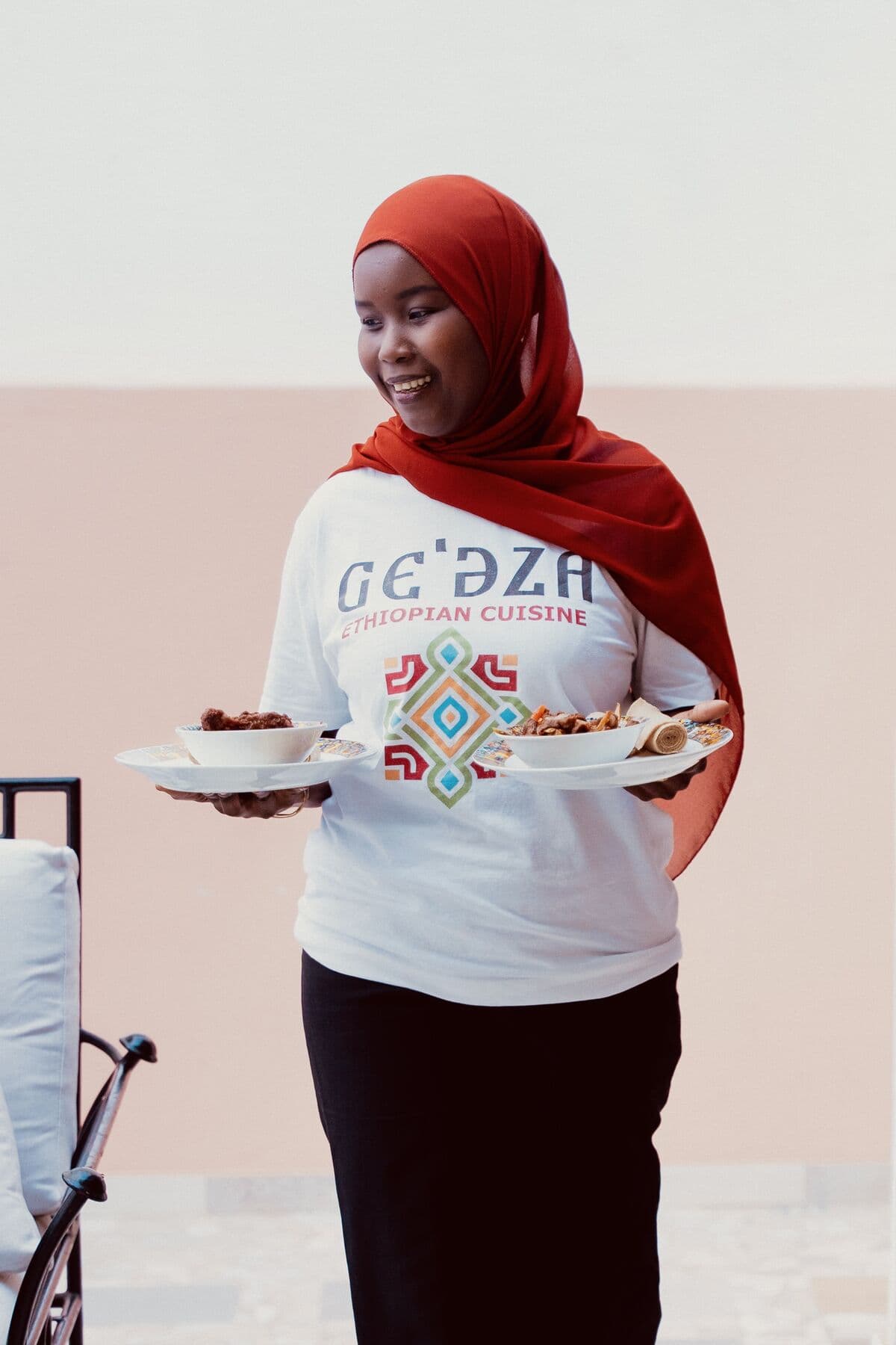Une serveuse apporte les plats en terrasse chez Ge'eza